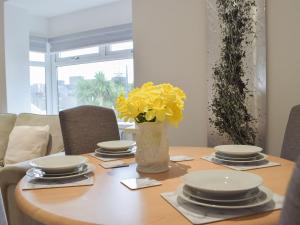 a table with plates and a vase with yellow flowers at Princess Court Apartment in Llanelli