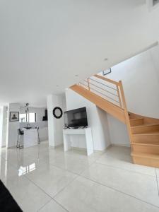 a white living room with a staircase and a television at Villa Moderne et Intimiste, à Quelques Minutes de la Baie de la BAULE in Pornichet