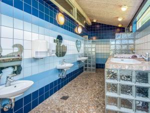 a blue tiled bathroom with two sinks and mirrors at 4 person holiday home in Hampen in Hampen +35 photos