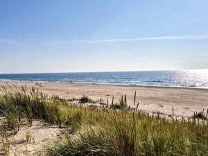 a beach with people on the sand and the ocean at 4 person holiday home in Ringkøbing-By Traum in Ringkøbing