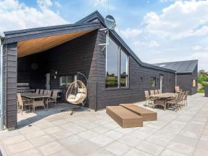 a patio with tables and chairs and a building at 5 star holiday home in Glesborg in Glesborg