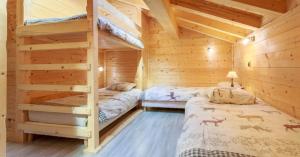 two beds in a log cabin bedroom with wooden walls at Gite Les Tarines 1 in Beaufort