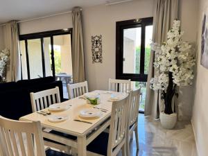a white dining room table with white chairs and flowers at Blanca, Marassiمراسي العلمين in El Alamein