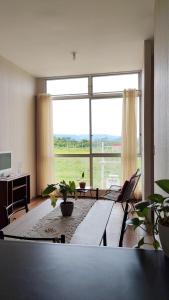 ein Wohnzimmer mit Tisch und großem Fenster in der Unterkunft Refugio Custodia 2 vista a montaña in Tarapoto