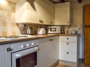 a kitchen with white cabinets and white appliances at Ivy Cottage in Elton