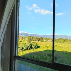 ein Fenster mit Blick auf ein Feld von einem Haus aus in der Unterkunft Refugio Custodia 2 vista a montaña in Tarapoto + 14 Fotos