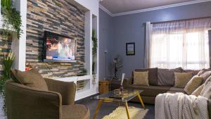 a living room with a couch and a tv on a brick wall at The apartments-Bwebajja in Bwebajja