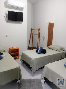 une chambre avec deux lits et une télévision à écran plat dans l'établissement Hotel Avenida, à Ribas do Rio Pardo