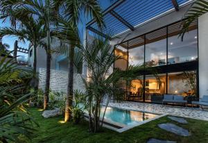 a house with a swimming pool and palm trees at Hum Living Luxury Villas in Tulum