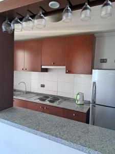a kitchen with brown cabinets and a white refrigerator at Dpto completo en Calama Centro in Calama