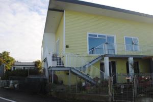a yellow house with stairs on the side of it at Hoki Boatshed Holiday Accommodation in Hokitika