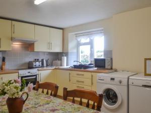 a kitchen with a washing machine and a table with chairs at East Monkton Farm Cottage in Wick +9 photos