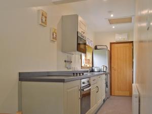 a kitchen with white cabinets and a black counter top at Waterfall Cottage in Tansley