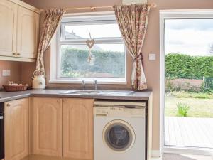 a kitchen with a washer and dryer next to a window at Princes Gate Cottage in Templeton