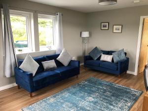 a living room with two blue couches and a rug at Caroy Bay Cottage-Uk32669 in Harlosh