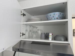 Una cocina con un estante con platos y botellas. en Royal appart city 1, en Calais 12 fotos más