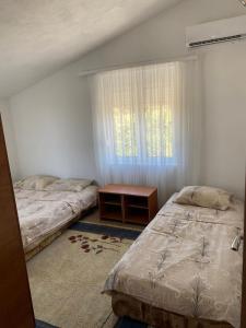 a bedroom with two beds and a table and a window at Apartments Nera in Utjeha
