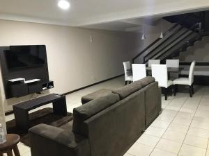 a living room with a couch and chairs and a television at Las Arecas - rucci 61 in Puerto Iguazú