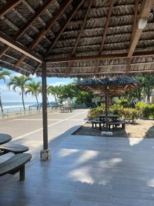 a patio with picnic tables and a beach with palm trees at Penthouse frente al mar in Tonsupa