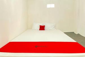 a red pillow sitting on a bed in a room at RedDoorz Yasmine Syariah near Taman Dayu in Jetak