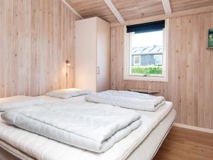 two beds in a room with wooden walls and a window at 4 star holiday home in Juelsminde in Sønderby