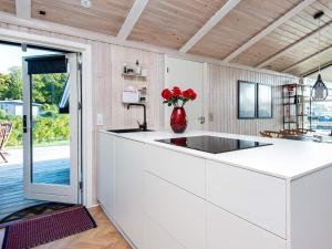 a kitchen with a counter with a vase of red roses at 4 star holiday home in Juelsminde in Sønderby