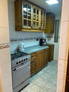 a kitchen with a stove and wooden cabinets at Hermosa casa en barrio residencial in Santiago