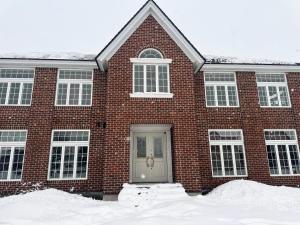 a brick house with a white door in the snow at BIEI TERRACE 1st Floor - 1F専用独立玄関 - 1F占有78平米大型ワンルーム- ソファベッド7台, 170型米Valerion社製最新シアター動画視聴, 無料Wi-Fi, シャワー, ミニキッチン付き - 駅前通り沿い - in Biei