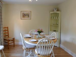 ein Esszimmer mit einem Holztisch und weißen Stühlen in der Unterkunft Broad Cottage Boathouse in Ranworth