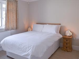 Un dormitorio con una cama con sábanas blancas y una ventana. en Riverside, en Bude