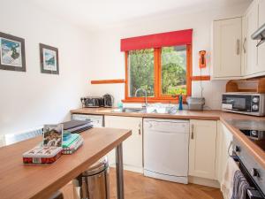 Una cocina con gabinetes blancos y un fregadero y una ventana. en Bidean Cottage - Uk41933, en Glencoe 9 fotos más