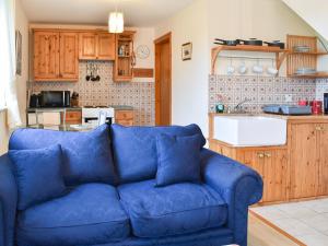 a blue couch in a living room with a kitchen at Ty Mawr 1 - Uk36545 in Nantlle