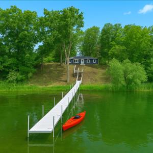 a red kayak sitting next to a dock on a lake at New! Private Lakefront Retreat 3BR 2BA Game Room 