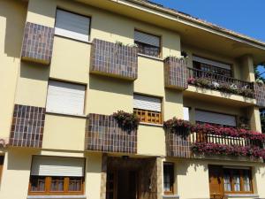 un edificio con ventanas y cajas de flores en los balcones en Pensión San Jorge, en Nueva de Llanes