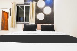 a bed with two pillows in a room with a window at Hotel O SR & Guest House 2 in Sakardarā