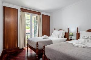 a white bedroom with two beds and a window at Pestanas Nest by Homie in Ribeira Brava
