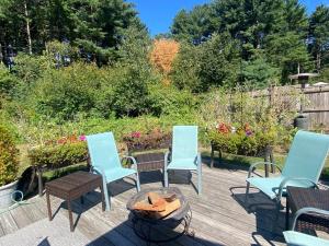 a patio with three chairs and a fire pit at Cozy en suite with high ceilings in Framingham