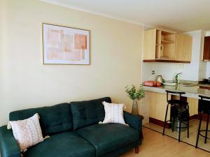 a living room with a green couch and a kitchen at Departamento 2 habitaciones in Temuco