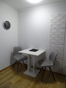 a white table with two chairs and a clock on a wall at Fewo Seeanker in Friedrichskoog