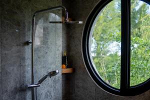 a bathroom with a shower and a round mirror at Nidya Villa Canggu in Canggu