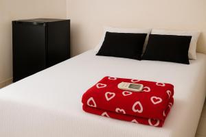 Una manta roja con un teléfono celular sobre una cama. en Apartamento com quarto e frigobar, en Santarém
