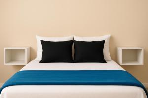 Una cama con dos almohadas blancas y negras encima. en Apartamento com quarto e frigobar, en Santarém