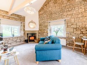 a living room with a blue couch and a stone wall at Shawdon Hill Coach House in Alnwick