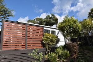 a house with a wooden fence and trees at Sundown Palms in Whangaparaoa