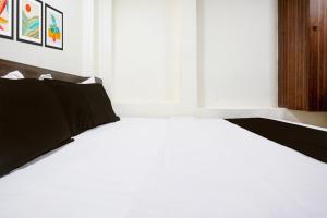 a white bed with black pillows in a bedroom at Hotel O Grand Villa in Mumbai +21 photos