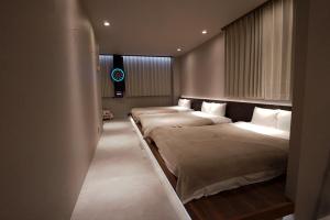 two beds in a hotel room with twothirdsessions at TABISAI HOTEL Luxe 博多 in Fukuoka