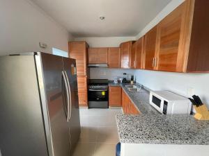 a kitchen with wooden cabinets and a stainless steel refrigerator at Comodo apartamento en Boca Chica SDQ AILA in El Higo