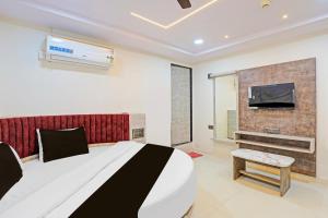 アーメダバードにあるFabHotel Malvaの大きなベッドと薄型テレビのある寝室