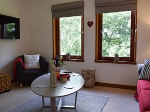 a living room with a table and two windows at Tree Tops in Crieff