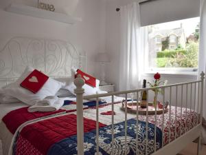 a white bed with a red and blue blanket and a window at Tree Tops in Crieff +7 photos